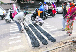 End of the story: Rumble strips, that had become a major source of inconvenience to commuters, being filled up by the Municipal Corporation staff at the Sector 19/20/27/30 roundabout in Chandigarh on Tuesday. Tribune photo: Manoj Mahajan