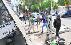 Dehradun Municipal Corporation workers remove encroachments from foot paths at Nehru Colony in Dehradun on Wednesday. a tribune photograph