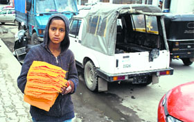 In violation of the Child Labour Act, a boy is seen selling flannel cloth to vehicle owners in Srinagar.