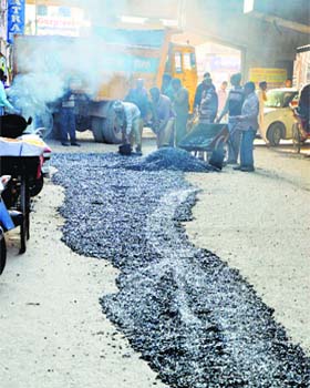 MC workers repair a stretch of road near Bhadaur House in Ludhiana on Thursday