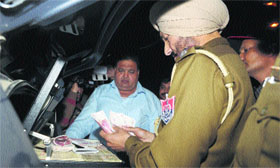 Policemen count cash recovered from an NRI at Wadala Chowk in Jalandhar on Friday.