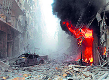 Debris cover a street and flames rise from a building following a reported air strike by Syrian government forces during the Friday prayers in the Sukkari neighborhood of the northern city of Aleppo