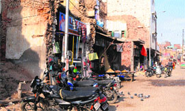 Shopkeepers continue their trade from tiny shops while demolished structures still lie in front of their shops in the Ghee Mandi area in Amritsar on Saturday.
