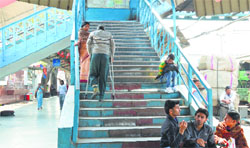 In the absence of a ramp or an escalator, a physically challenged person climbs stairs at the railway station in Ludhiana. Photo: Inderjeet Verma