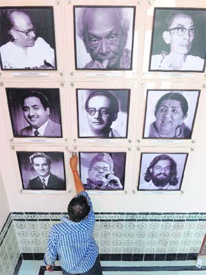 A National Council of Science Museums employee cleans photographs of legendary music directors and singers at the National Museum of Indian Cinema (NMIC) in Mumbai