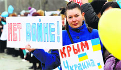 An anti-war protester holds placards reading 'no war' and 'Crimea is Ukraine' during a rally in Simferopol on Saturday. Reuters