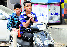 A teenager plays a stunt while driving a two-wheeler on a road in Amritsar