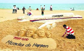 Sand artist Sudarsan Pattnaik creates a sand sculpture on the missing Malaysian Airlines flight MH370 with a message Pray God Miracles do Happen at Puri beach of Odisha on Sunday