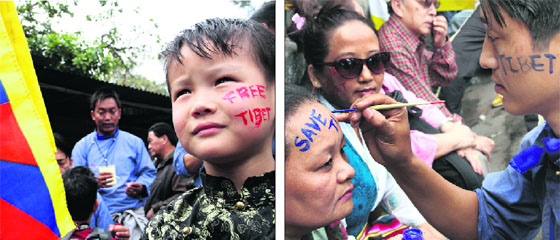 A Tibetan child holds a flag of Tibet with a slogan written on his cheek; and (right) a Tibetan woman getting slogans painted on her face before the start of the Tibetan Uprising Day procession in Dehradun on Monday.