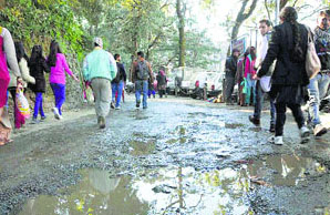 Commuters walk on a potholed road in Shimla.