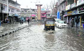 Vehicles make way through a water-logged road at Lal Chowk in Srinagar