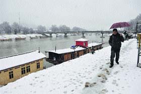 Wearing white: A man walks on the banks of the Jhelum in Srinagar, which received 3 inches of snow on Sunday night