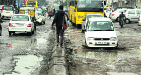 Commuters face a tough time crossing the potholes filled with rainwater in Jalandhar on Saturday.