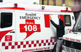 A health worker covers the picture of Chief Minister Parkash Singh Badal on an 108 ambulance in Jalandhar on Monday.