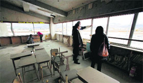 Visitors stand at the deserted Okawa Elementary School where scores of students went missing following the 2011 tsunami in Ishinomaki, Miyagi prefecture, on Monday.