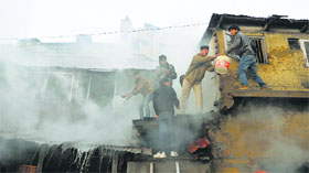 Fire-fighters help in rescue operation after a building caught fire in Shimla on Tuesday.