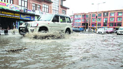 Vehicles pass through a waterlogged road at Lal Chowk in Srinagar. Tribune photo: Yawar Kabli