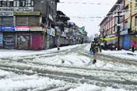 A CRPF jawan patrolling a snow-covered street as shops remain closed following heavy snowfall in Srinagar on Tuesday. Tribune photo: Amin War 