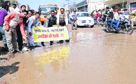 Congress leaders hold a protest on rainwater filled Garha Road against the ruling party leaders in Jalandhar on Wednesday