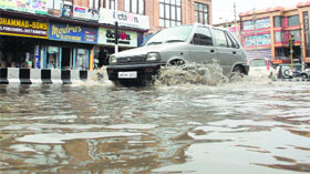 A car passes through a waterlogged road at Lal Chowk in Srinagar on Thursday.