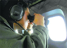 A crew member from the Royal Malaysian Air Force uses binoculars onboard a Malaysian Air Force aircraft during a search operation in the Straits of Malacca on Thursday