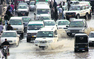Vehicles drive through a water-logged road in Srinagar.