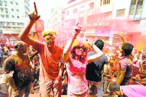 Foreign tourists daubed in colours dance as they celebrate Holi in Guwahati