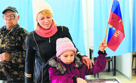 A child casts her mother's ballot while holding a Russian flag in Simferopol on Sunday.