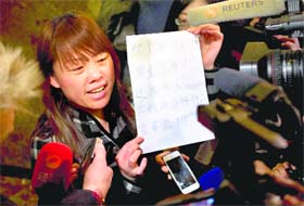 A relative of a Chinese passenger aboard the missing Malaysia Airlines Flight MH370 shows a paper reading Hunger strike protest, Respect life, Return my relative, Don't want become victim of politics, Tell the truth as she speaks to the media outside a hotel ballroom in Beijing on Tuesday