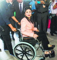 Thai Prime Minister Yingluck Shinawatra arrives on a wheelchair at the Royal Police Cadet Academy in Nakorn Pathom province.