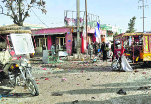 People stand near the debris at the site of a blast at Faryab in northern Afghanistan on Tuesday.