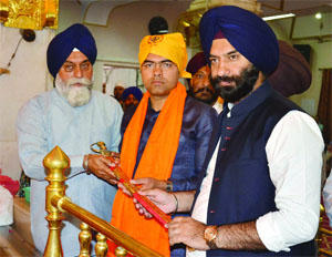 BJP candidate Pravesh Verma (C) being felicitated by DSGMC members Kuldeep Singh Bhogal (L) and Manjeet Singh Sirsa (R) at Gurdwara Bangla Sahib in New Delhi on Wednesday