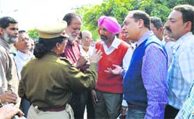 Members of the Teja Singh Sutantar Muhalla Sudhar Committee talk to a police official during their protest outside the PSPCL office at Kitchlu Nagar