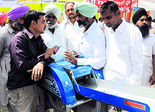 Farmers enquire about a modified agriculture fodder plant-cutter during the Kisan Mela in Bathinda on Friday