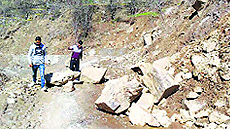 People walk on the damaged Doda-Bharat road
