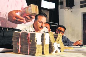 Officials count currency notes during the auction of liquor vends at Red Cross Bhawan in Jalandhar on Saturday