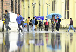People walk with umbrellas after a hailstorm on The Ridge in Shimla on Saturday.
