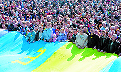 People hold a huge flag, a combination of a Ukrainian, Crimean and Tatar flags, at the Independence Square in Kiev on Sunday