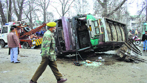 A police crane lifts a bus that had overturned after skidding on a rain-drenched road in Srinagar on Monday. Ten persons were injured in the incident.