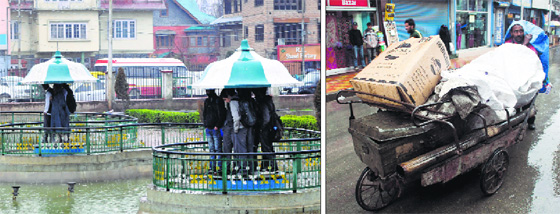 Schoolchildren take shelter at Partap Park in Srinagar; and (right) a man pushes his hand cart during heavy rainfall in the Kashmir valley on Monday.