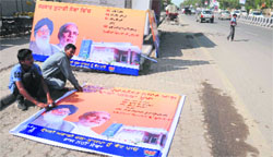 Workers put up posters of the SAD-BJP at a bus shelter on the GT Road in Bathinda on Tuesday. a Tribune photograph