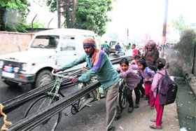Schoolchildren help a rickshaw puller carrying heavy load in Dehradun on Tuesday.