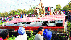 People try to move a bus which met with an accident on the Amritsar-Mehta road on Wednesday