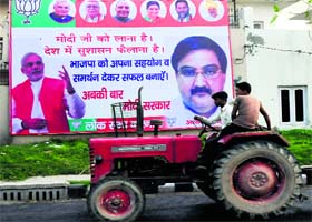 People pass by a hoarding of BJP PM candidate Narendra Modi and candidate from Karnal Ashwini Chopra in Karnal on Wednesday