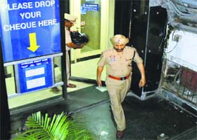 Police officials come out from a bank after seizing cash from DSP GS Bains’ accounts in Ludhiana on Thursday