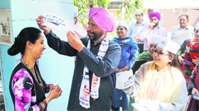 AAP candidate Dr Daljit Singh offers a cap to a woman during the election campaign in Amritsar on Saturday.