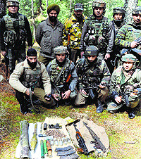 Army personnel display arms and ammunition recovered from a militant hideout in Baramulla district on Sunday