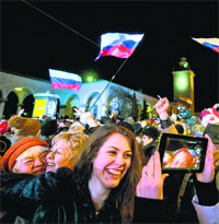 People celebrate the transition to Moscow time near a city clock tower at a railway station in Simferopol on Sunday.