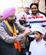 Dr Daljit Singh offers an AAP cap to a child during the election campaign in Amritsar on Monday.