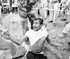 Policemen arrest a man who threw a slipper at Bihar Chief Minister Nitish Kumar during an election meeting in Khusrupur, Bihar, on Monday.